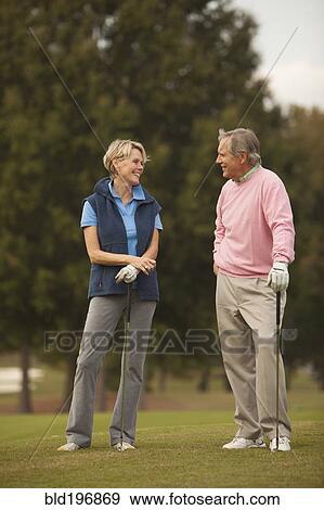 Couple standing on golf course View Large Photo Image Stock Photo - Couple standing on golf course. Fotosearch