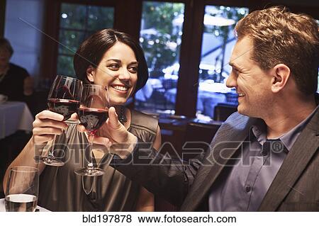 Couple toasting with red wine in restaurant View Large Photo Image Stock Photo - Couple toasting with red wine in restaurant. Fotosearch