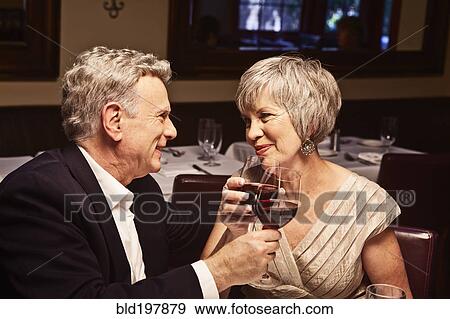 Couple toasting with red wine in restaurant View Large Photo Image Stock Photo - Couple toasting with red wine in restaurant. Fotosearch
