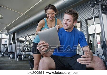 Couple using digital tablet in health club View Large Photo Image Stock Image - Couple using digital tablet in health club. Fotosearch
