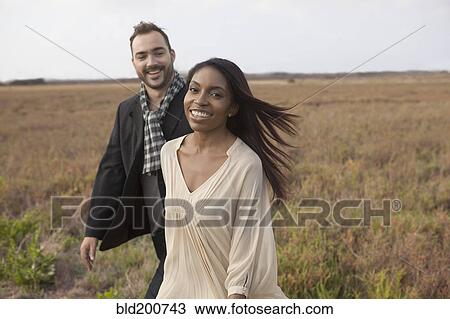 Stock Image - Couple walking in field. Fotosearch