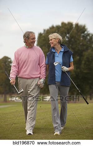 Stock Image - Couple walking on golf course. Fotosearch