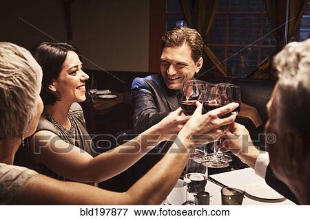 Stock Photo - Couples toasting with red wine in restaurant. Fotosearch