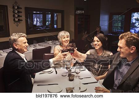 Stock Photograph - Couples toasting with red wine in restaurant. Fotosearch