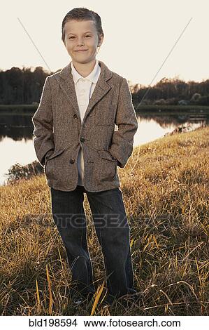 Picture - Cute boy in jacket standing near lake. Fotosearch
