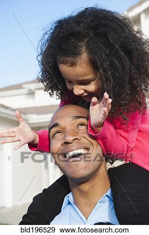 Daughter riding on father's shoulders View Large Photo Image Stock Photo - Daughter riding on father's shoulders. Fotosearch