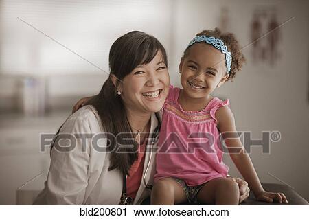 Stock Image - Doctor and girl smiling in doctor's office. Fotosearch