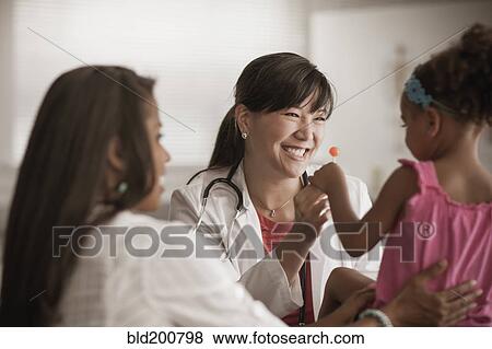 Stock Photo - Doctor handing girl lollipop. Fotosearch
