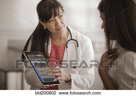 Stock Image - Doctor showing digital tablet to patient. Fotosearch