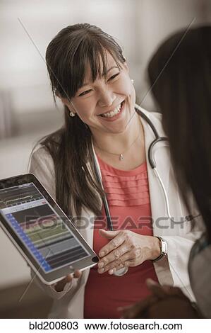 Stock Image - Doctor showing digital tablet to patient. Fotosearch
