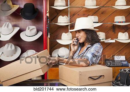 Ecuadorian woman talking on cell phone in hat store View Large Photo Image Picture - Ecuadorian woman talking on cell phone in hat store. Fotosearch