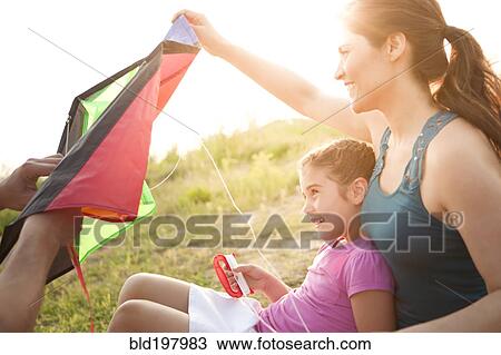 Stock Image - Family preparing to fly kite. Fotosearch