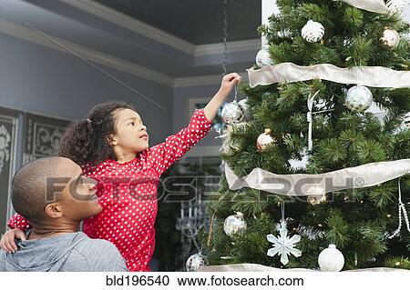 Stock Image - Father and daughter decorating Christmas tree. Fotosearch
