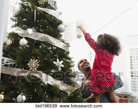 Stock Photo - Father and daughter decorating Christmas tree. Fotosearch