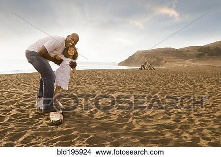 Picture - Father and daughter smiling on beach. Fotosearch