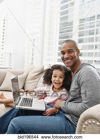 Father and daughter using laptop on sofa View Large Photo Image Picture - Father and daughter using laptop on sofa. Fotosearch