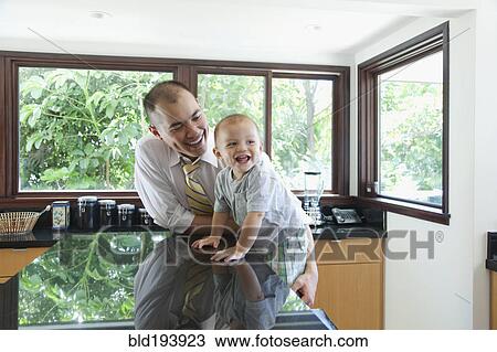 Stock Image - Father and son in kitchen. Fotosearch