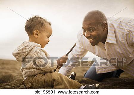 Stock Image - Father and son playing on beach. Fotosearch