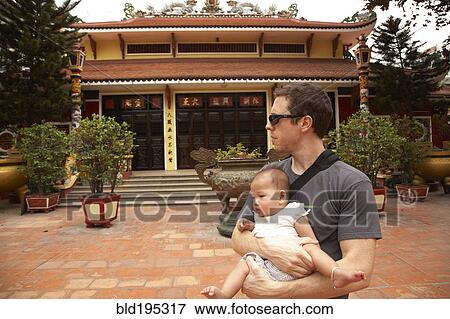 Stock Photo - Father carrying baby girl in courtyard. Fotosearch