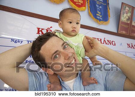 Stock Image - Father carrying baby on shoulders. Fotosearch