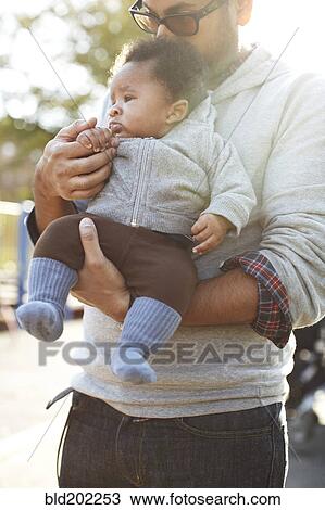 Stock Image - Father holding African American baby boy. Fotosearch