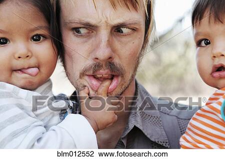 Stock Image - Father holding baby boys. Fotosearch