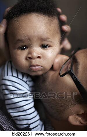 Stock Image - Father kissing African American baby. Fotosearch
