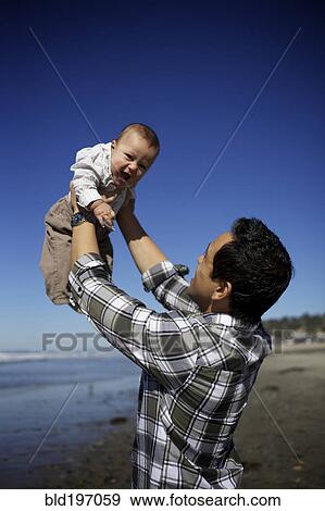 Stock Photo - Father lifting baby on beach. Fotosearch