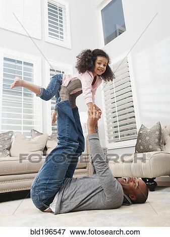 Stock Photo - Father lifting daughter on his feet. Fotosearch