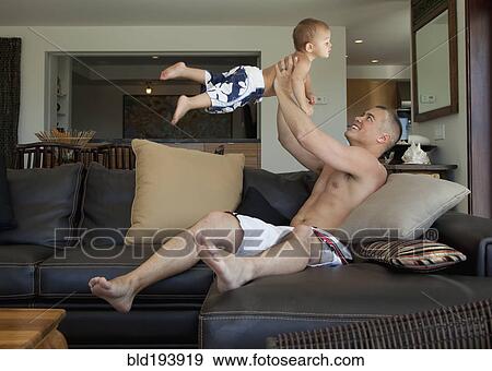 Stock Photo - Father lifting son in living room. Fotosearch