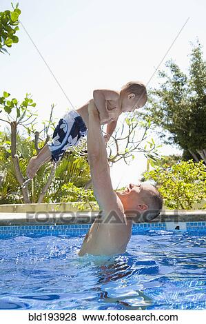 Stock Photo - Father lifting son in swimming pool. Fotosearch