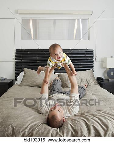 Father lifting son on bed in bedroom View Large Photo Image Stock Photography - Father lifting son on bed in bedroom. Fotosearch