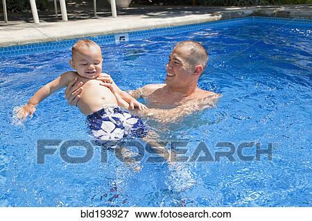 Stock Photo - Father playing with son in swimming pool. Fotosearch