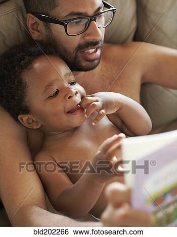 Stock Photograph - Father reading book to African American baby. Fotosearch