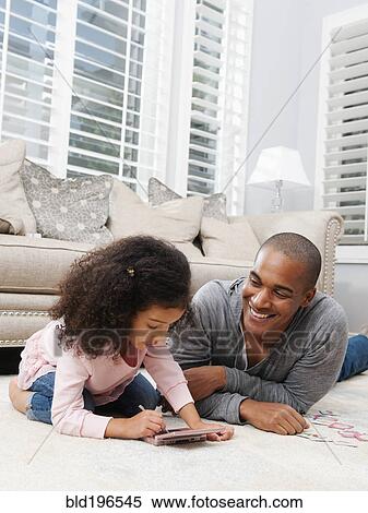 Father watching daughter play video game View Large Photo Image Stock Photography - Father watching daughter play video game. Fotosearch