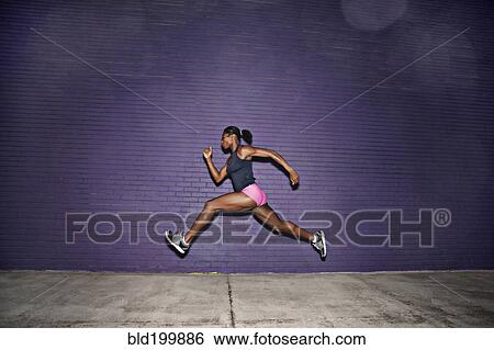 Stock Photograph - Female athlete running on sidewalk. Fotosearch