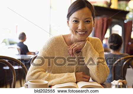 Stock Photography - Filipino woman reading book in cafe. Fotosearch