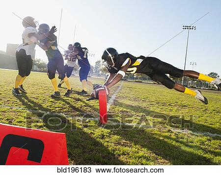 Stock Image - Football player scoring goal on football field. Fotosearch