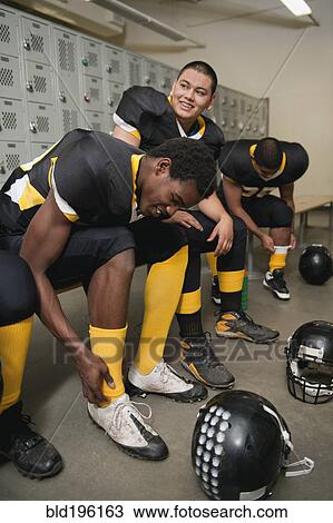 Stock Image - Football players dressing in locker room. Fotosearch