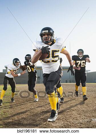 Stock Image - Football players playing on football field. Fotosearch