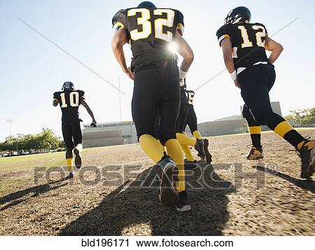 Stock Image - Football players running on football field. Fotosearch
