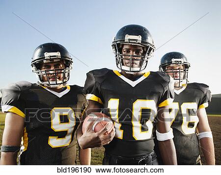 Stock Image - Football players standing on football field. Fotosearch