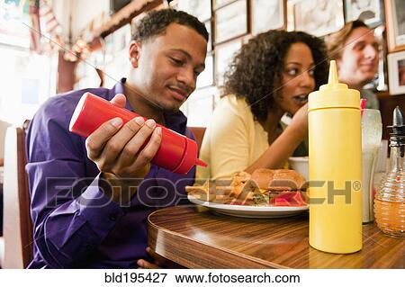 Stock Photo - Friends eating in diner booth. Fotosearch