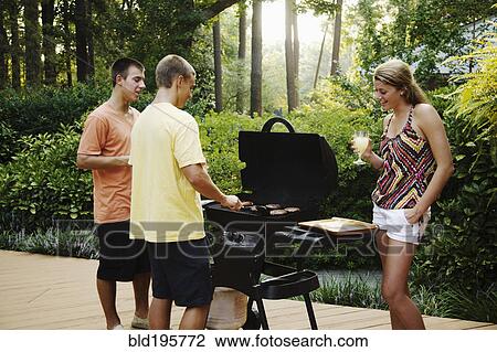 Stock Image - Friends hanging out together barbecuing. Fotosearch
