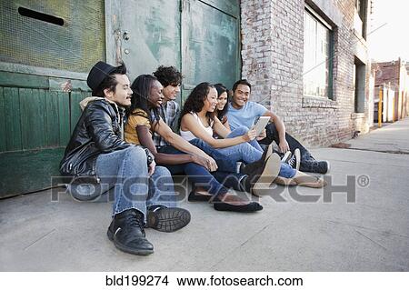 Picture - Friends hanging out together in urban area using digital tablet. Fotosearch