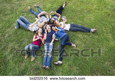 Friends hanging out together on grass View Large Photo Image Stock Photograph - Friends hanging out together on grass. Fotosearch