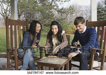 Stock Photo - Friends playing scrabble on porch. Fotosearch