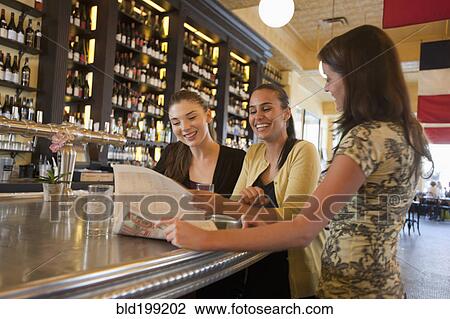Stock Image - Friends relaxing in restaurant bar together. Fotosearch