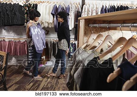 Stock Image - Friends shopping together in clothing store. Fotosearch