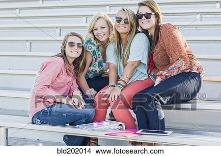 Picture - Friends sitting on bleachers. Fotosearch